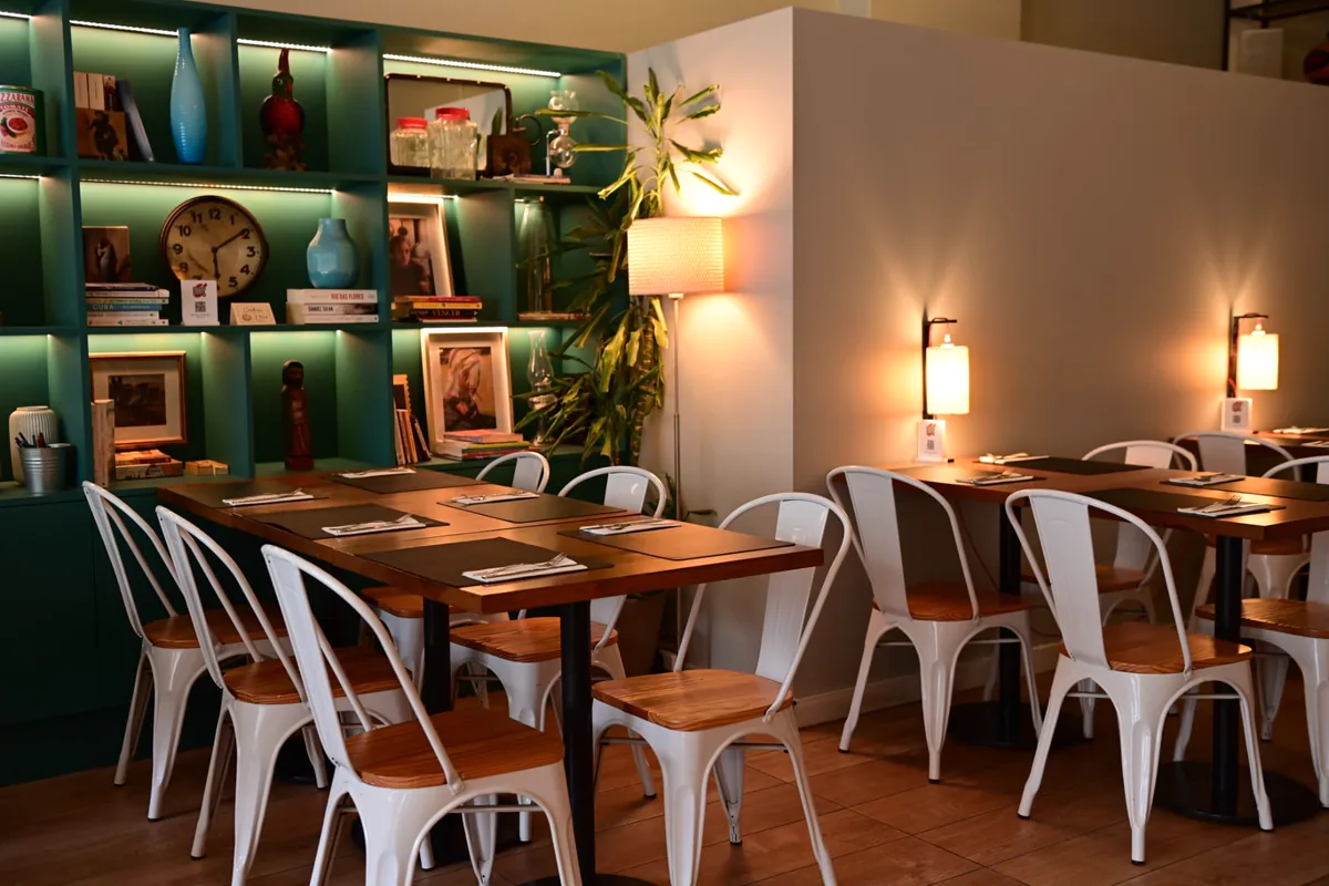 Sala do Porto - Pinheiro Manso, com candeeiros quentes, estante verde e mesas preparadas