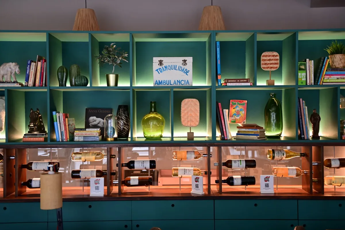Estante verde com livros, plantas e garrafas de vinho no Matosinhos